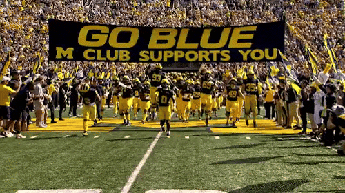 Michigan touches the banner on its way to the field